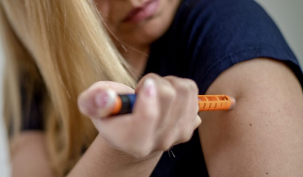 Young woman injecting insulin in hers arm at home